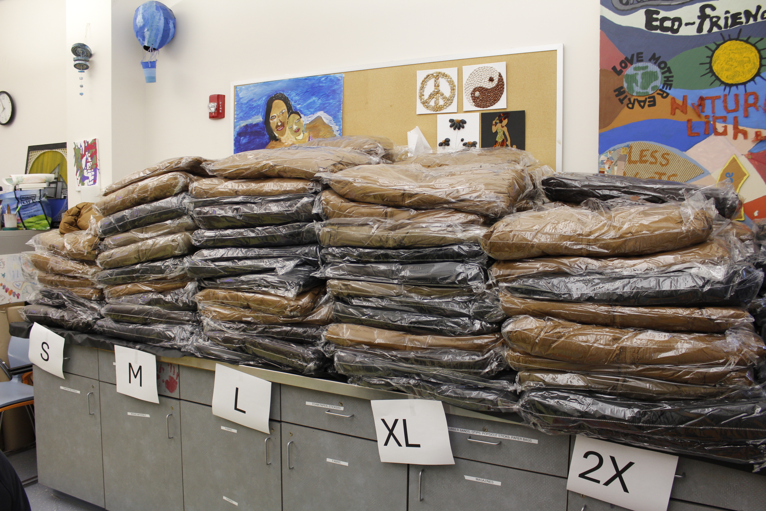 Piles of coats on a countertop with signs indicated size.