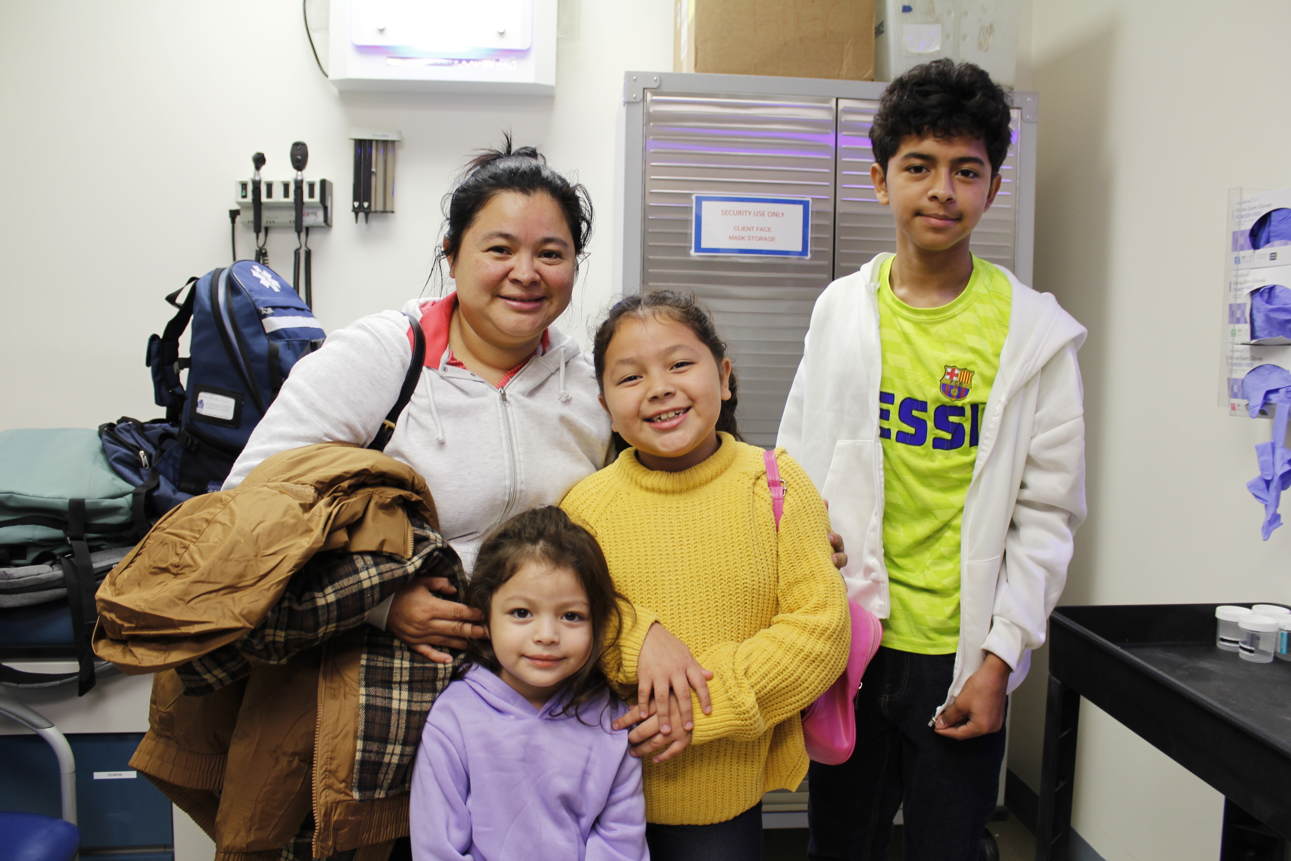 A family of a mother, son and two daughters smile after receiving their flu shots.