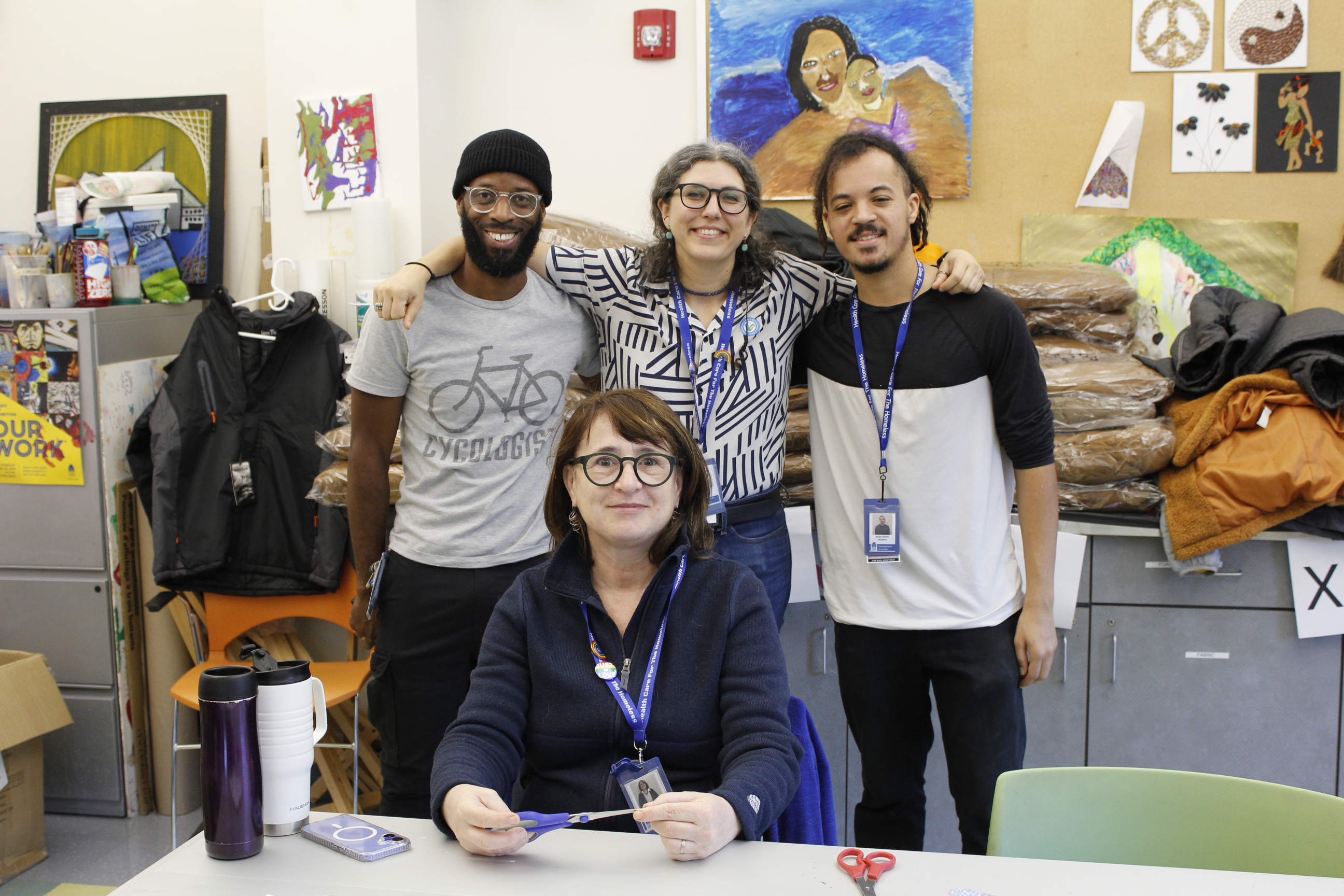 A group of staff members pose in front of stacks of coats.