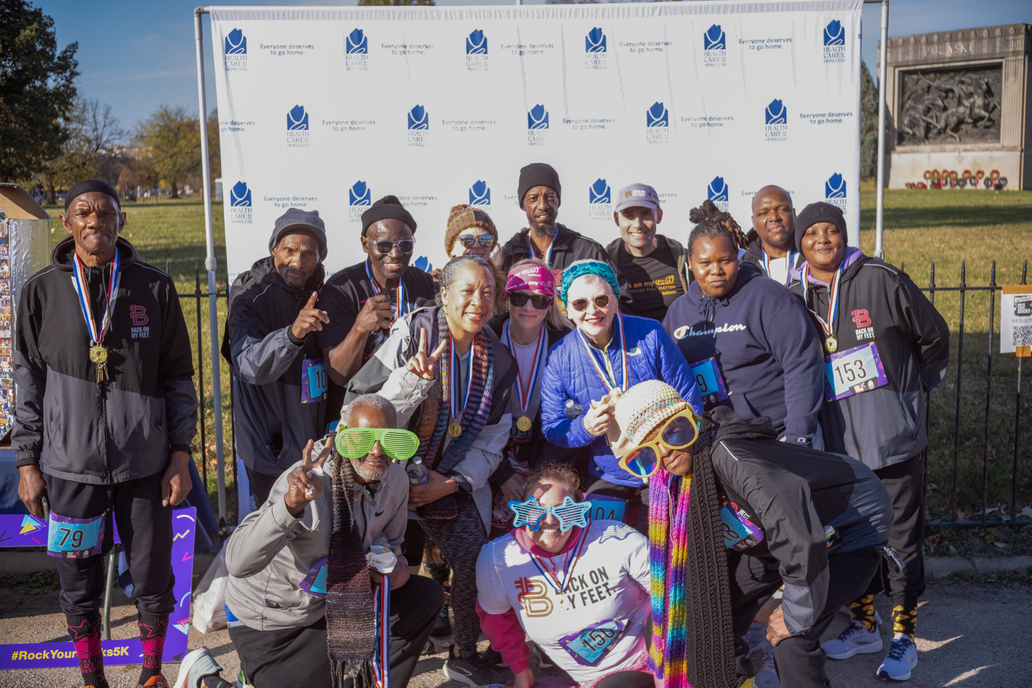 A large group post in front of the Health Care for the Homeless step-and-repeat.