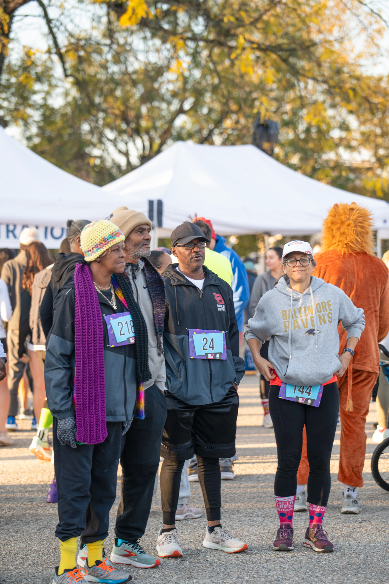 A group of 5K participants stand in front of white tents.