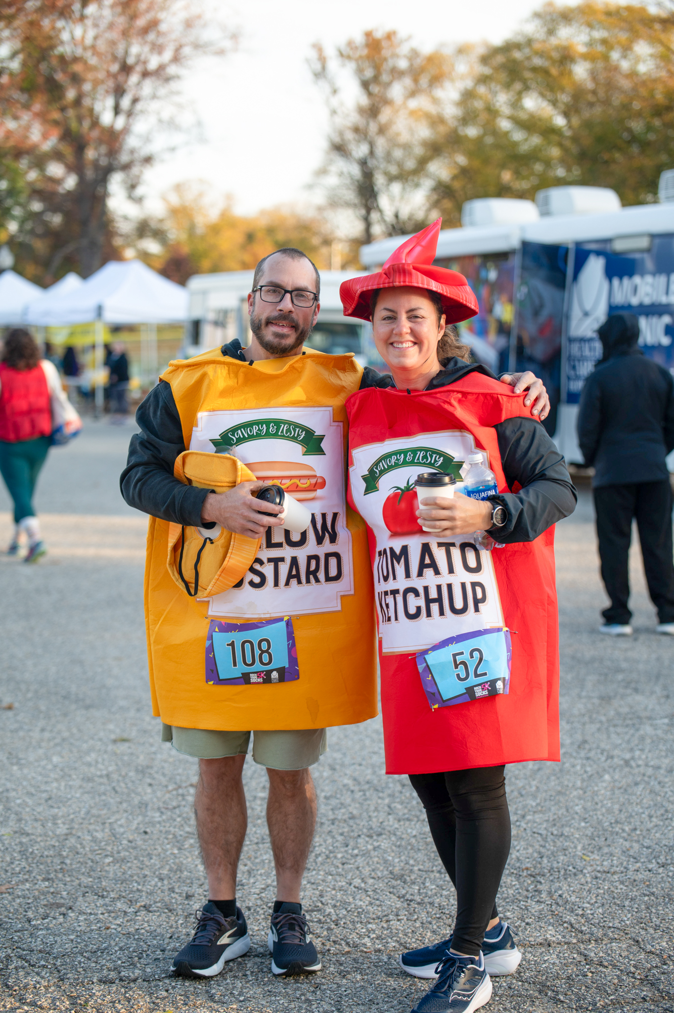 A light-skinned man dressed as mustard and a light-skinned woman dressed as ketchup.