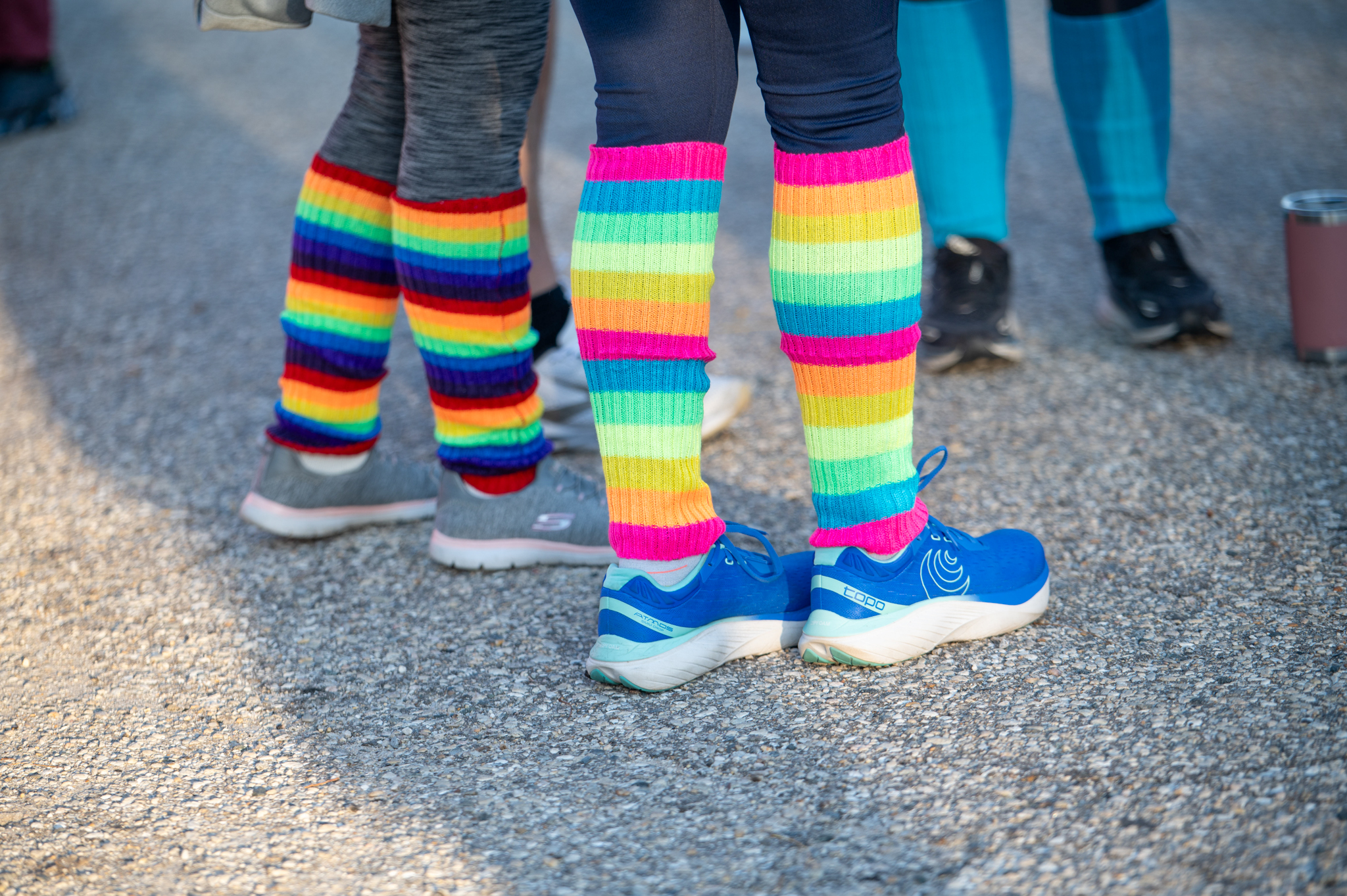 Two people's legs. They wear rainbow striped socks.