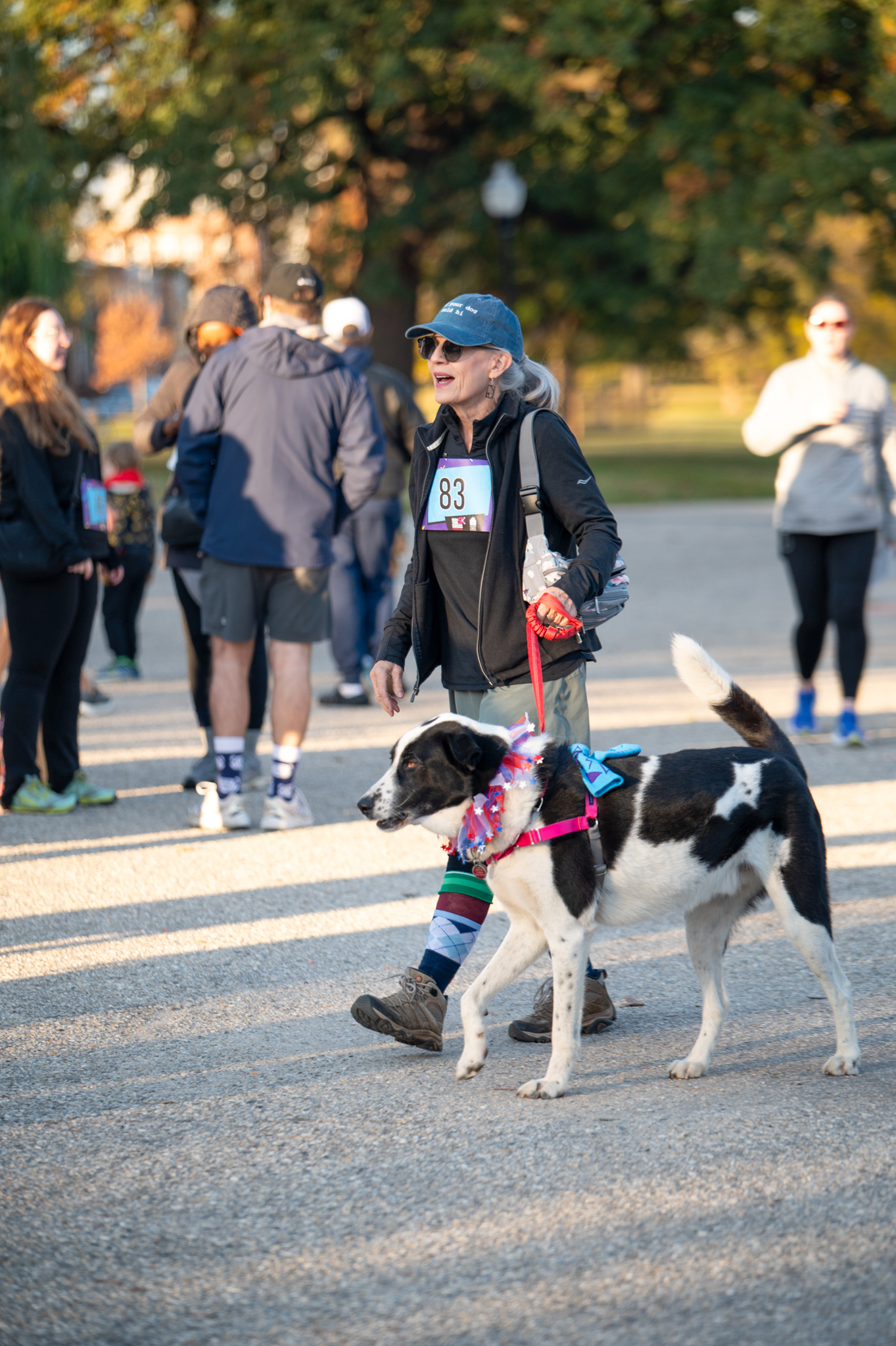 A light-skinned woman walks with her black and white dog.