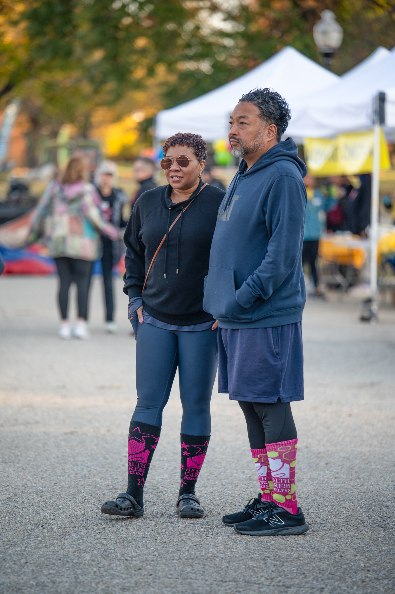 A medium-skinned woman in a black sweatshirt and a medium-skinned man in a blue sweatshirt.