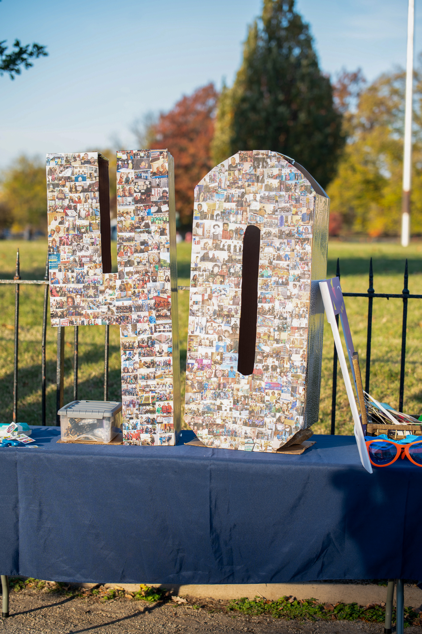 A large "40" made out of cardboard and covered with photos sits on a table with a blue table cloth.