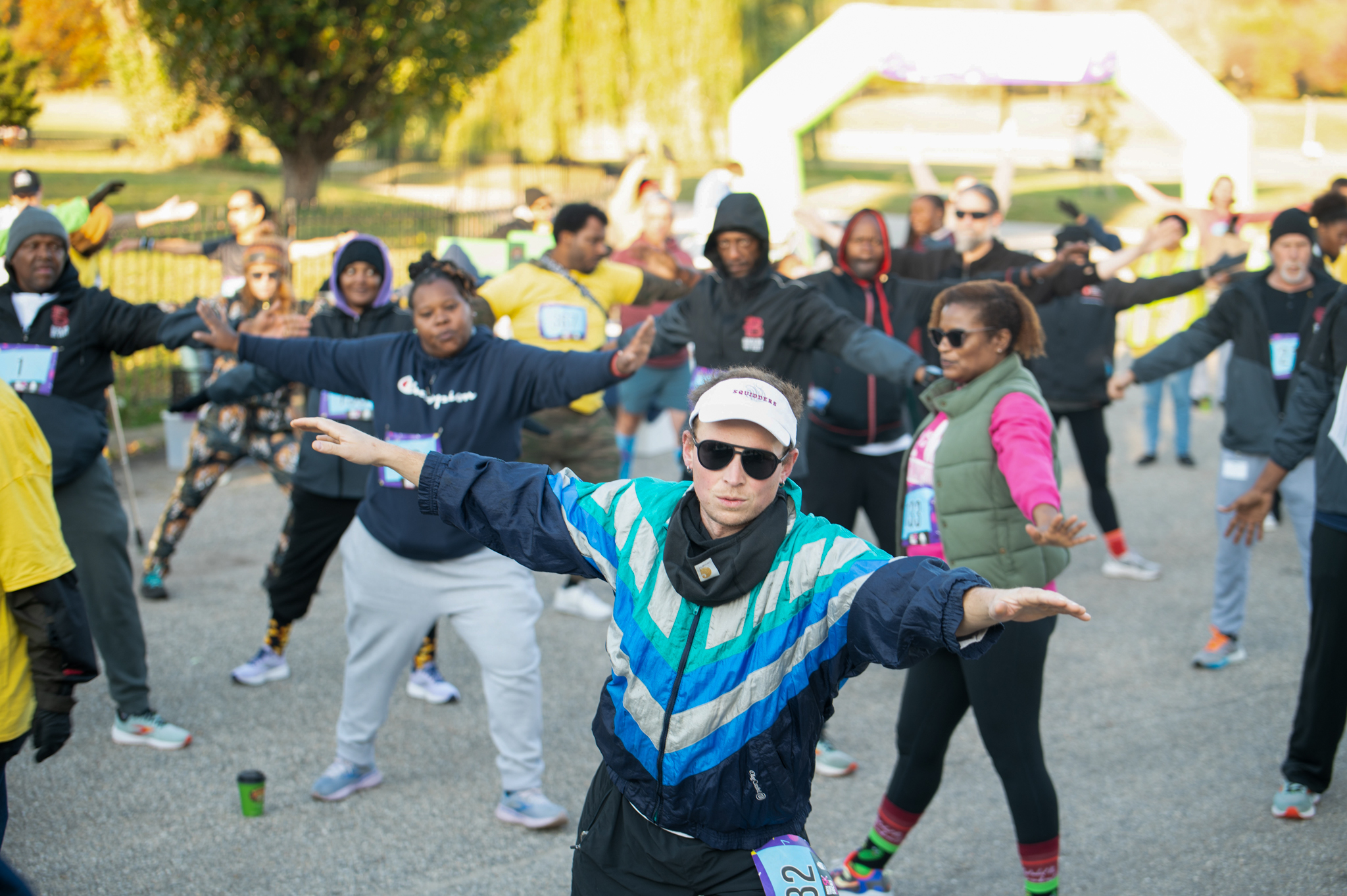 A group of 5K participants stretch with their arms out and their feet apart.
