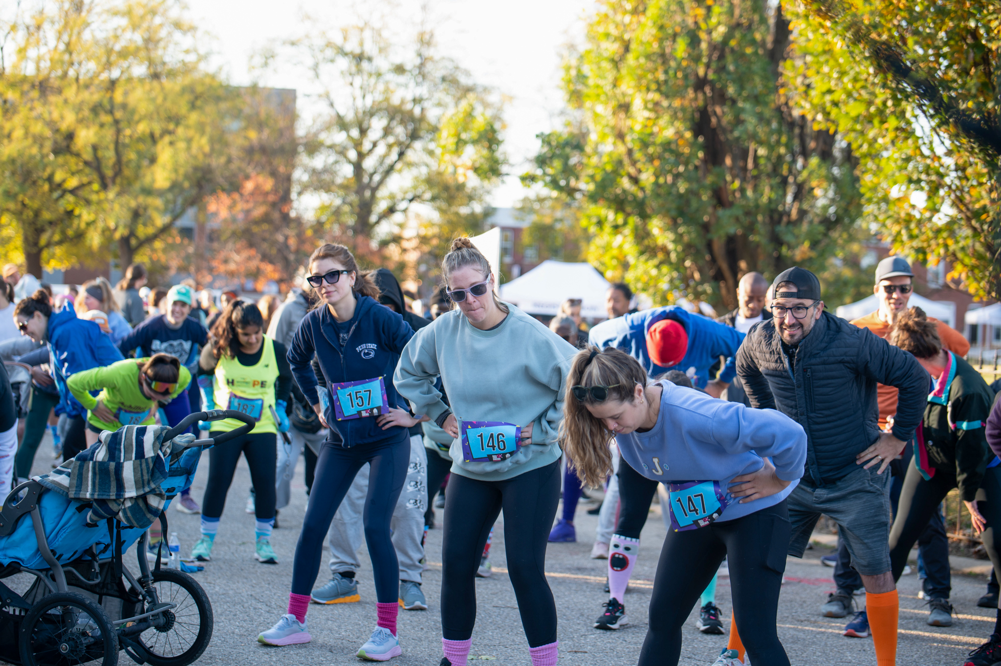A group of 5K participants bend with their hands on their hips.