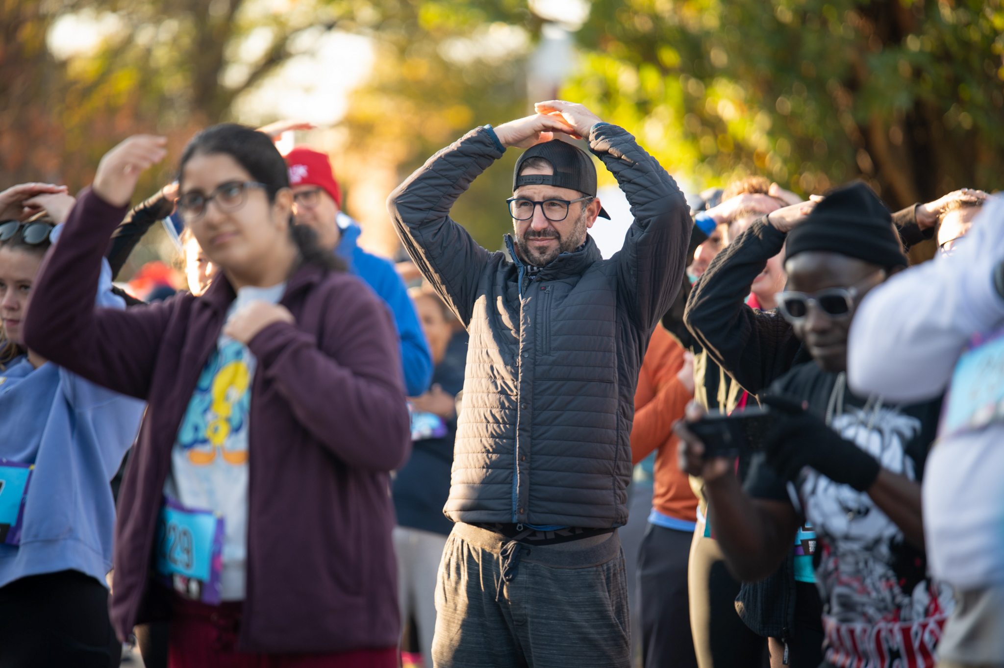 A group of 5K participants place their hands on their heads.