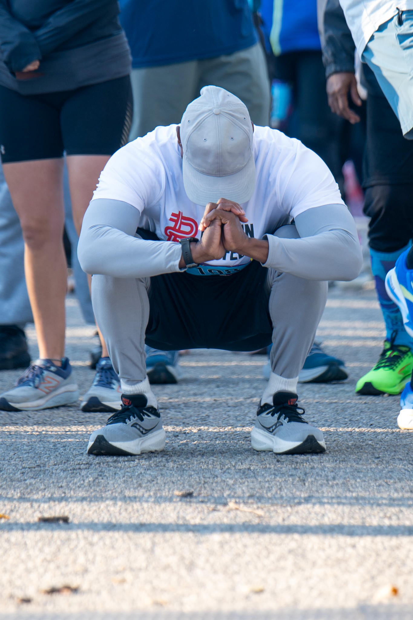 A person at the starting line squats with their head down.