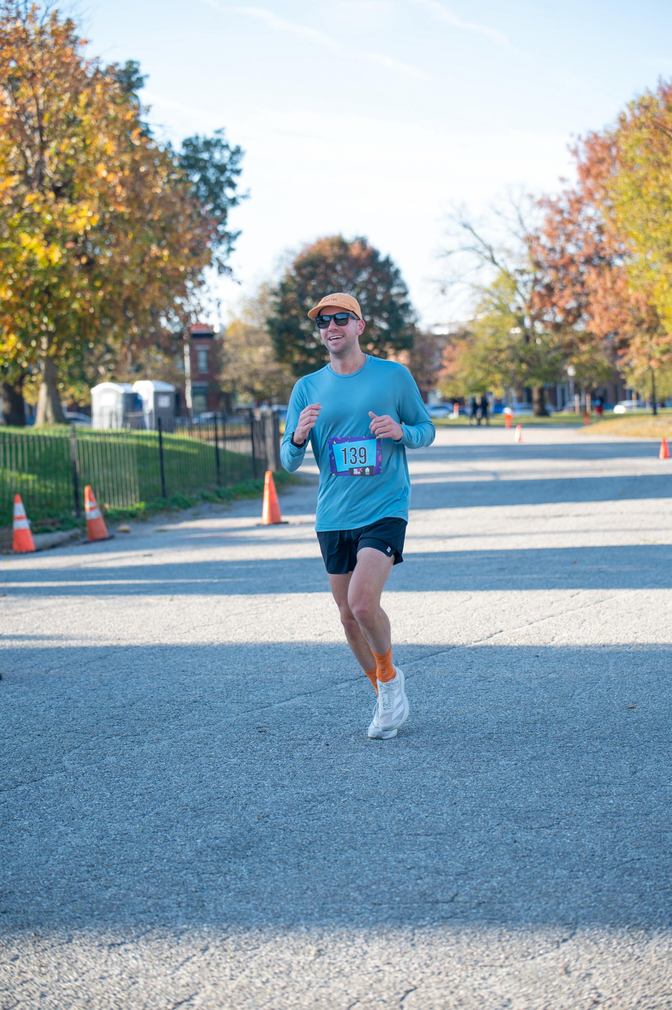 A light-skinned woman runs in a blue long sleeve shirt and black shorts
