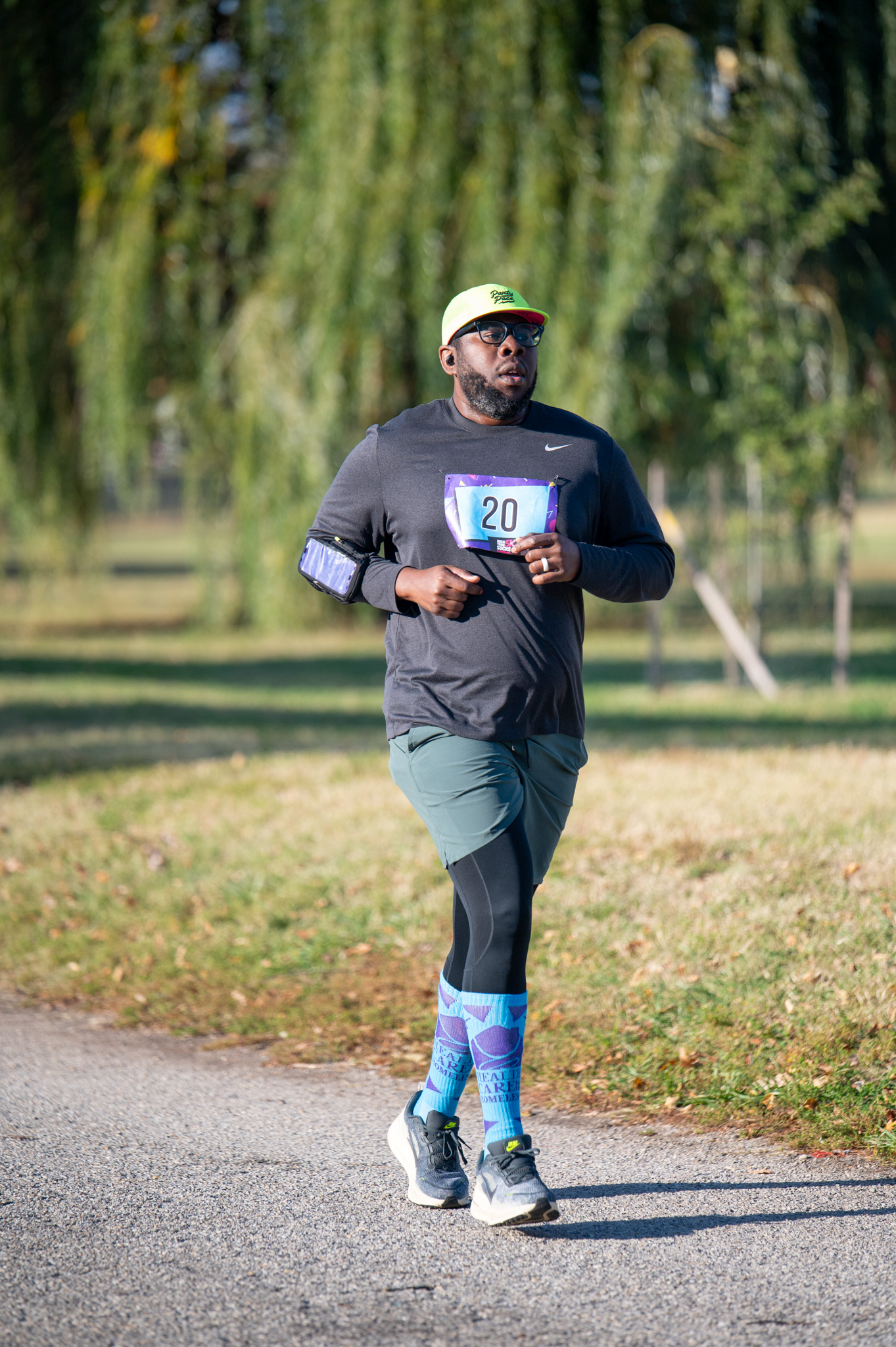 A dark-skinned man in a black top and green shorts jogs