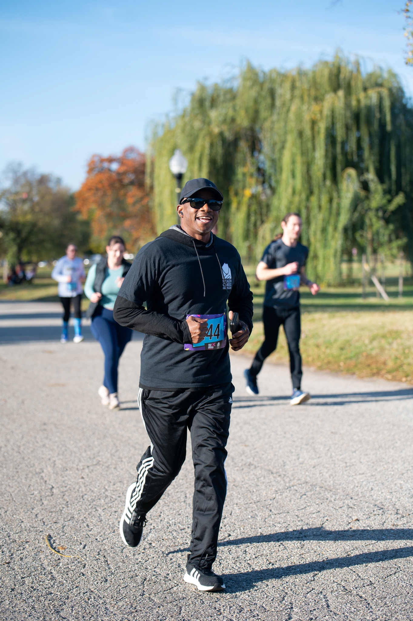 A dark-skinned man in a black shirt and black pants jogs