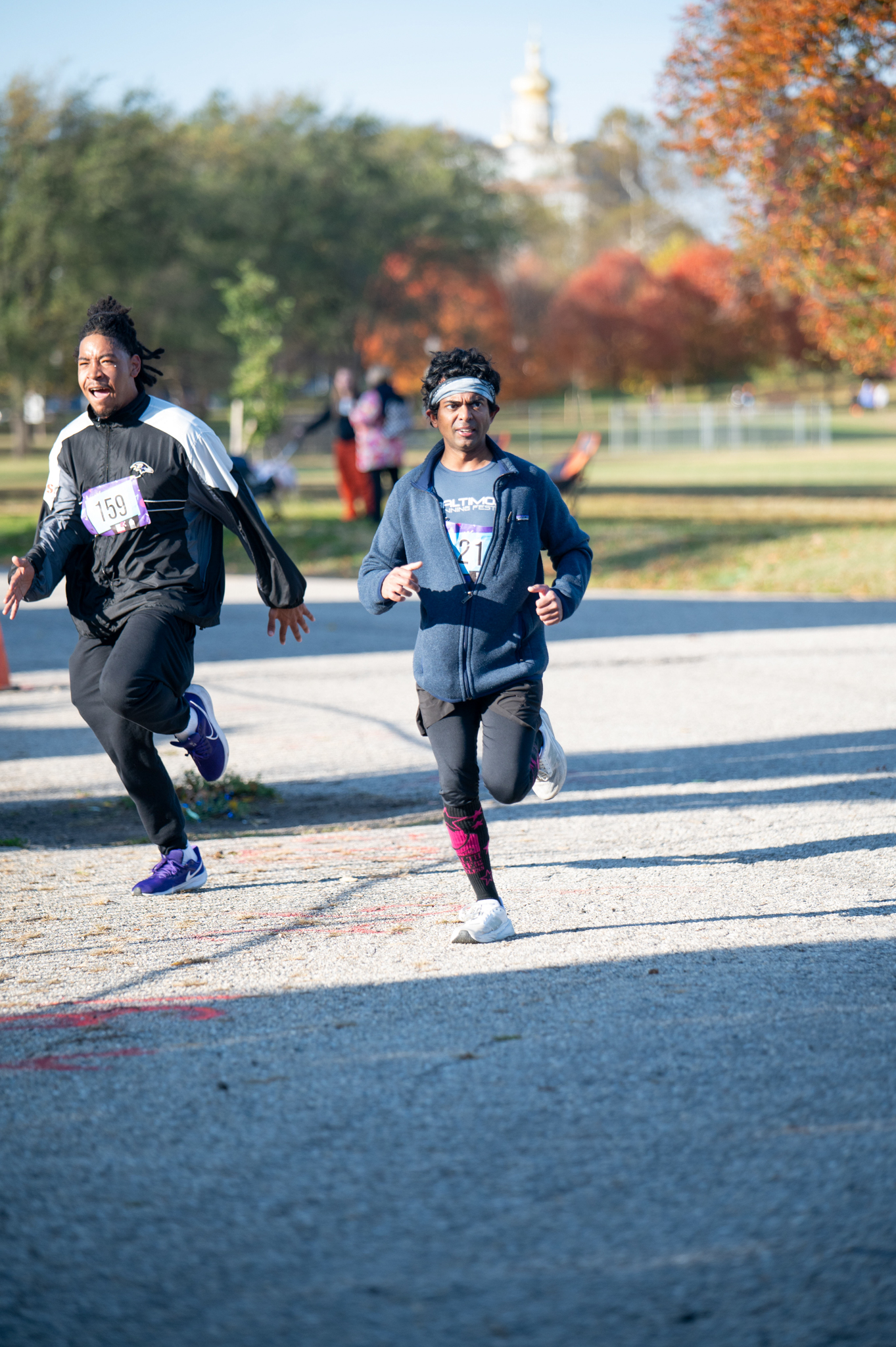 A medium-skinned man in a grey jacket sprints to the finish line
