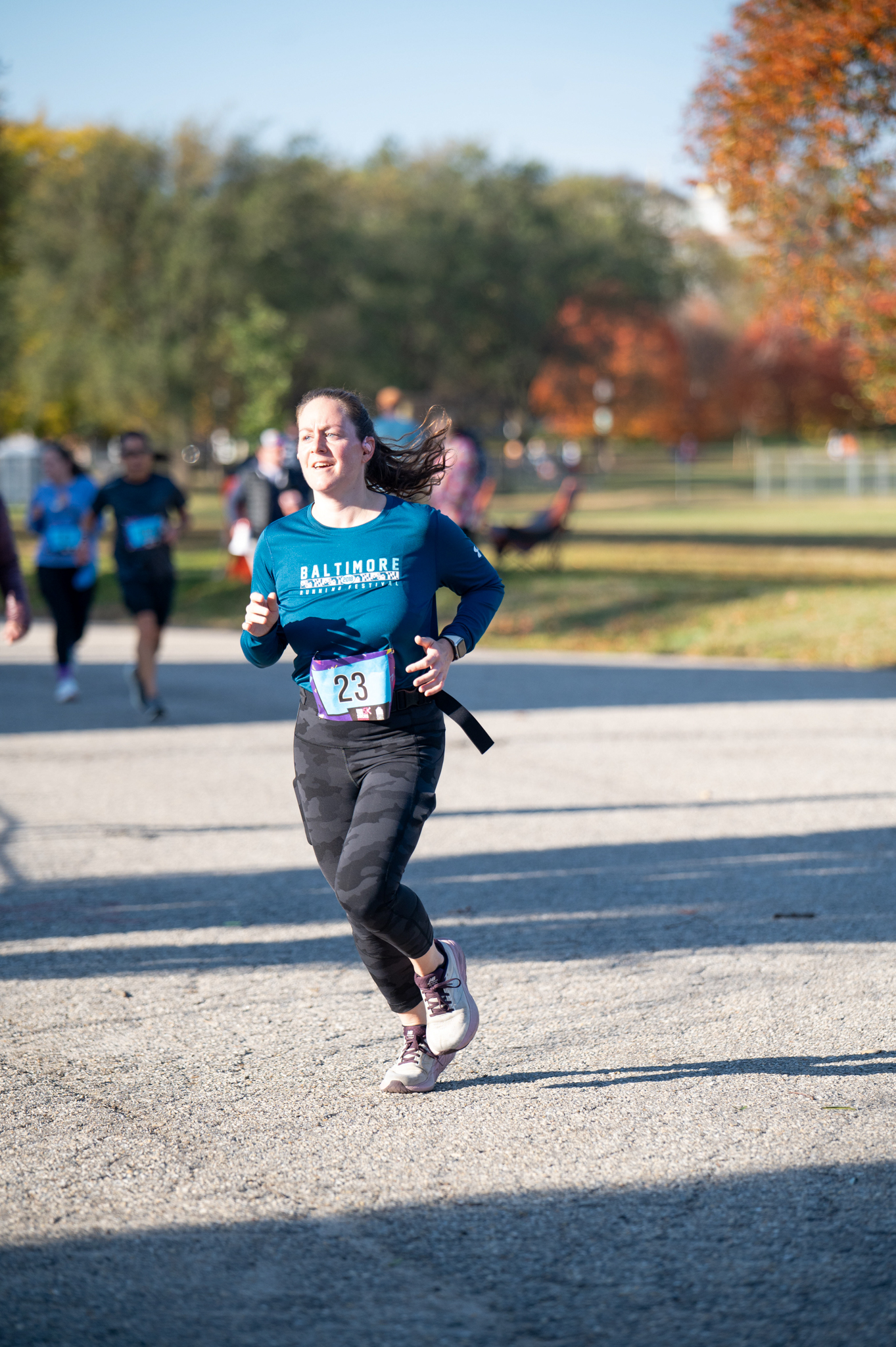 A light-skinned woman in a blue top and grey camo leggings jogs