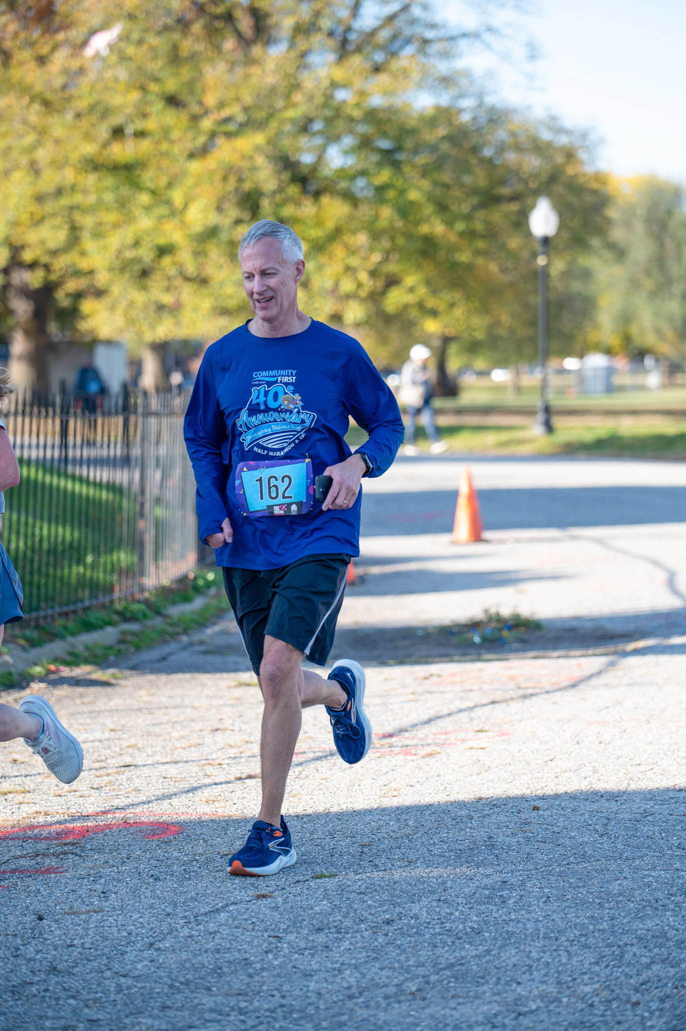 A light-skinned man in a purple top and black shorts jogs