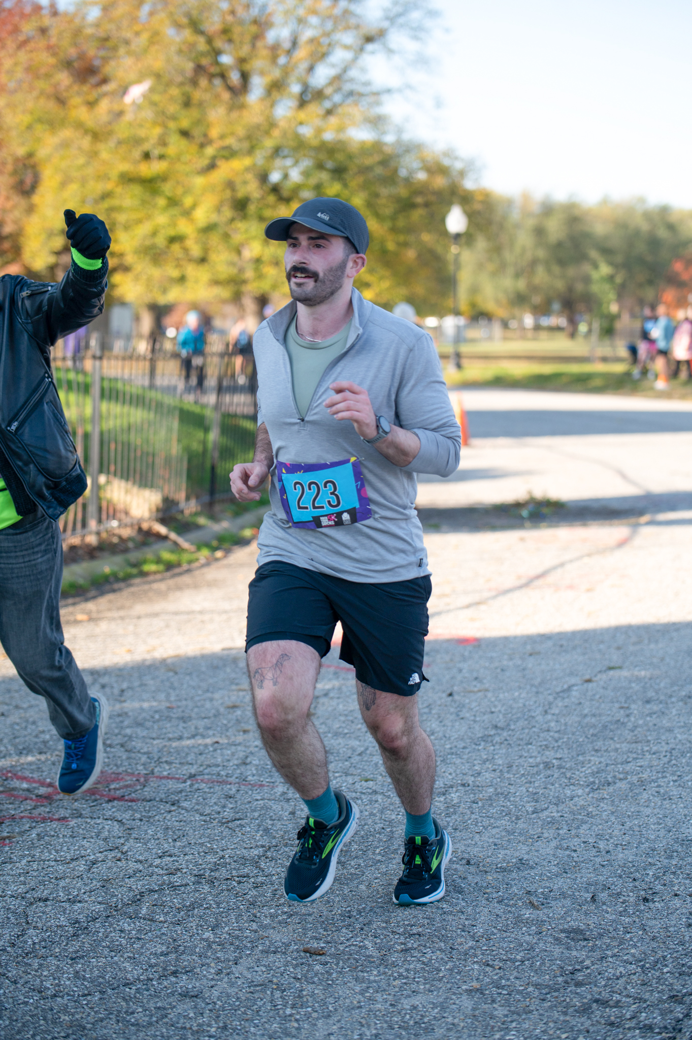 A light-skinned man in a grey athletic top and black shorts jogs