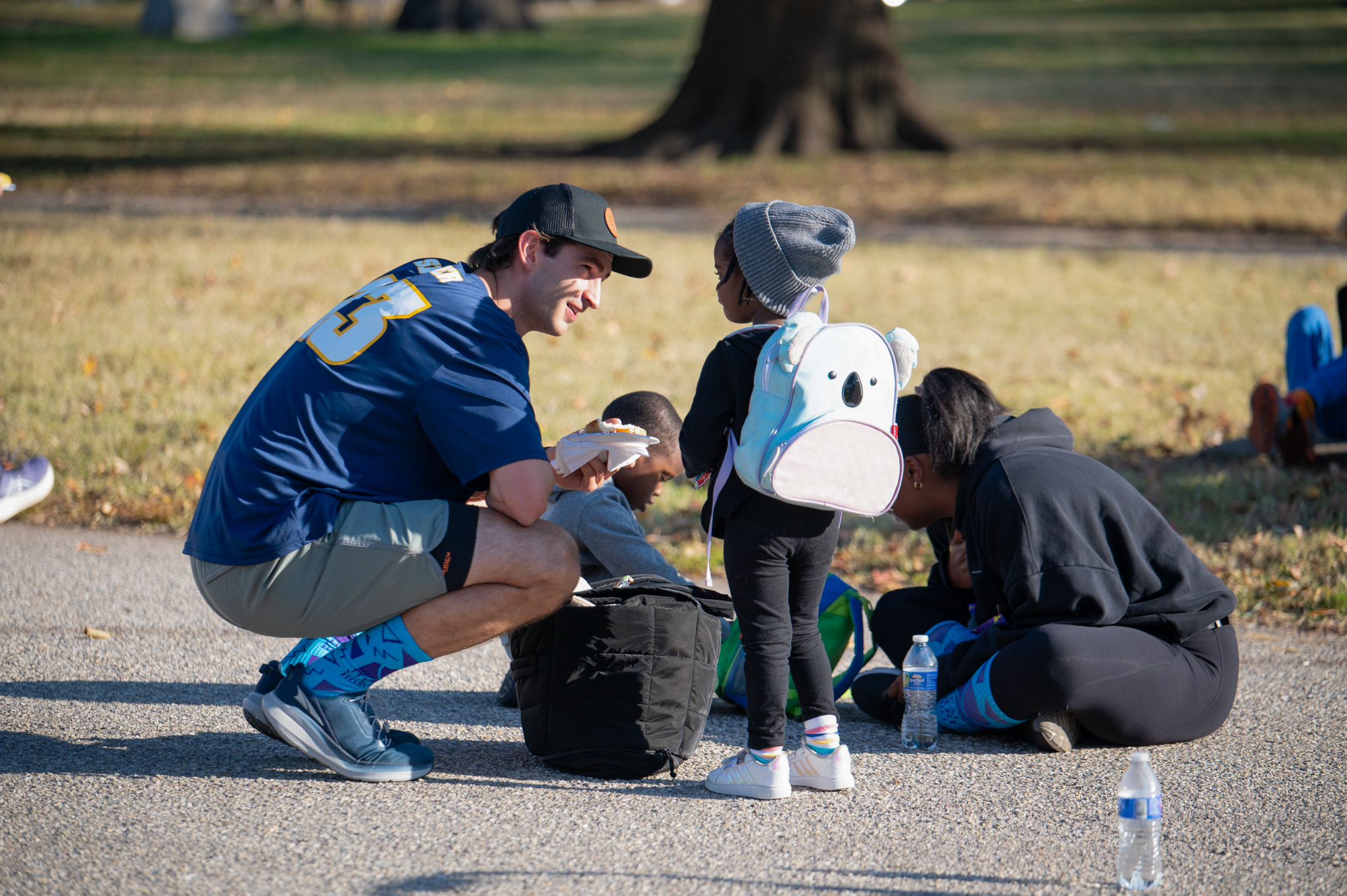 A group of adults and children gather with backpacks and water bottles.