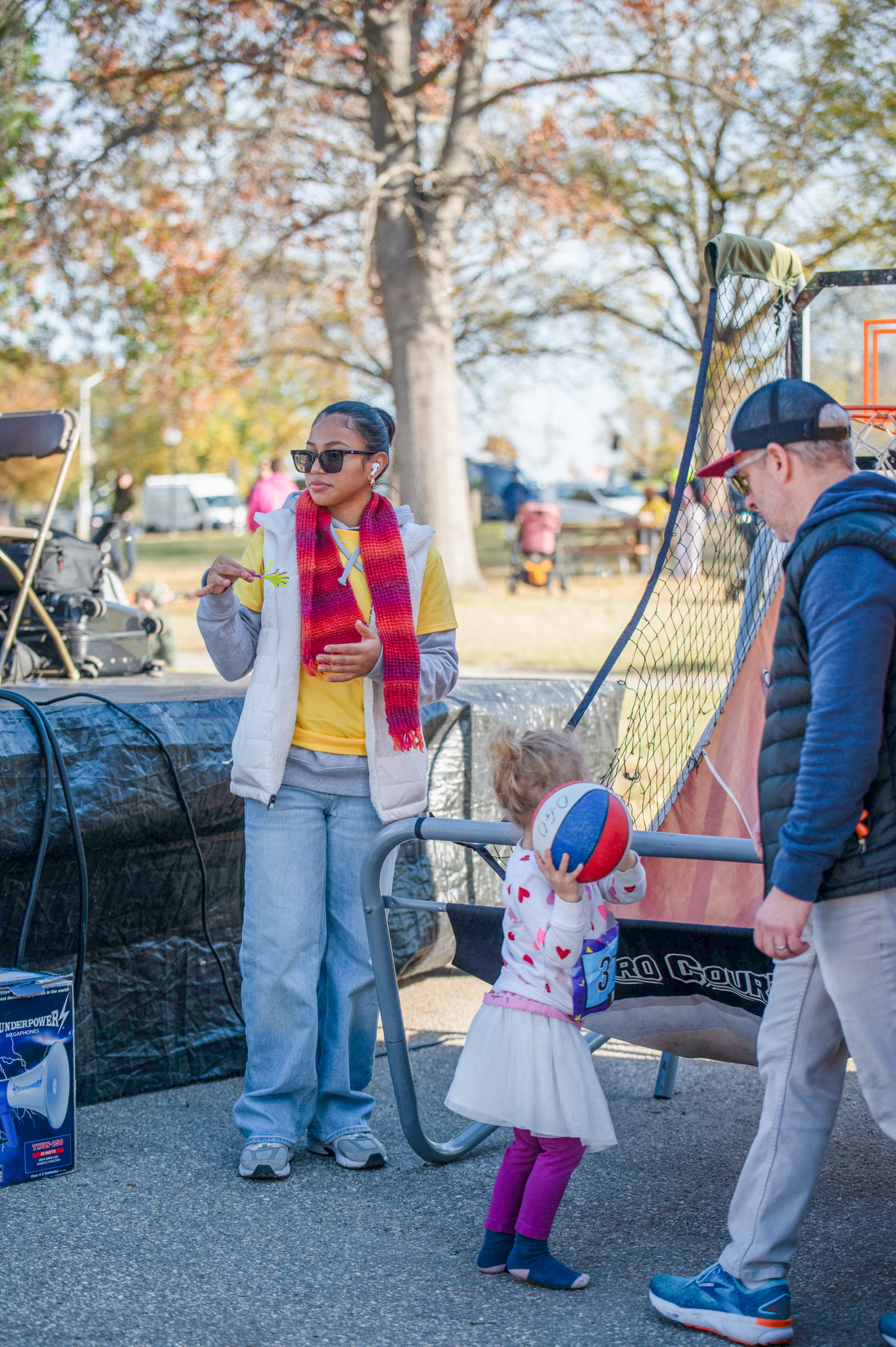 A girl wearing a tutu holds a small basketball in front of the basketball hoop game