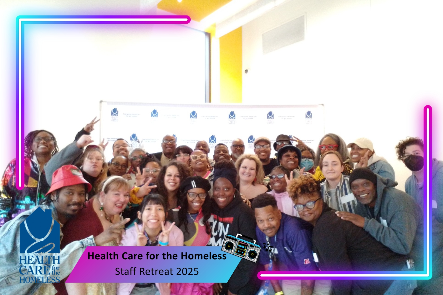 Large group in front of a blue and white backdrop holding 80s photobooth props