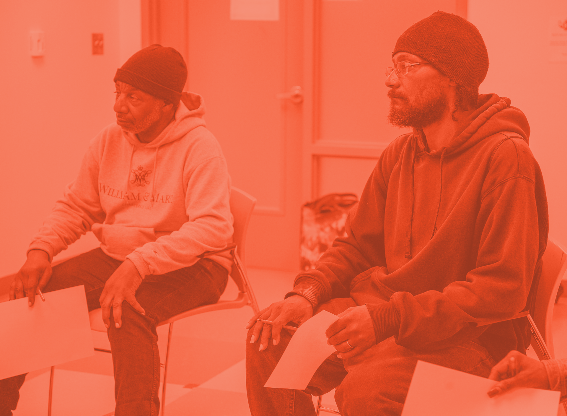Two clients sit in chairs at a support group meeting.