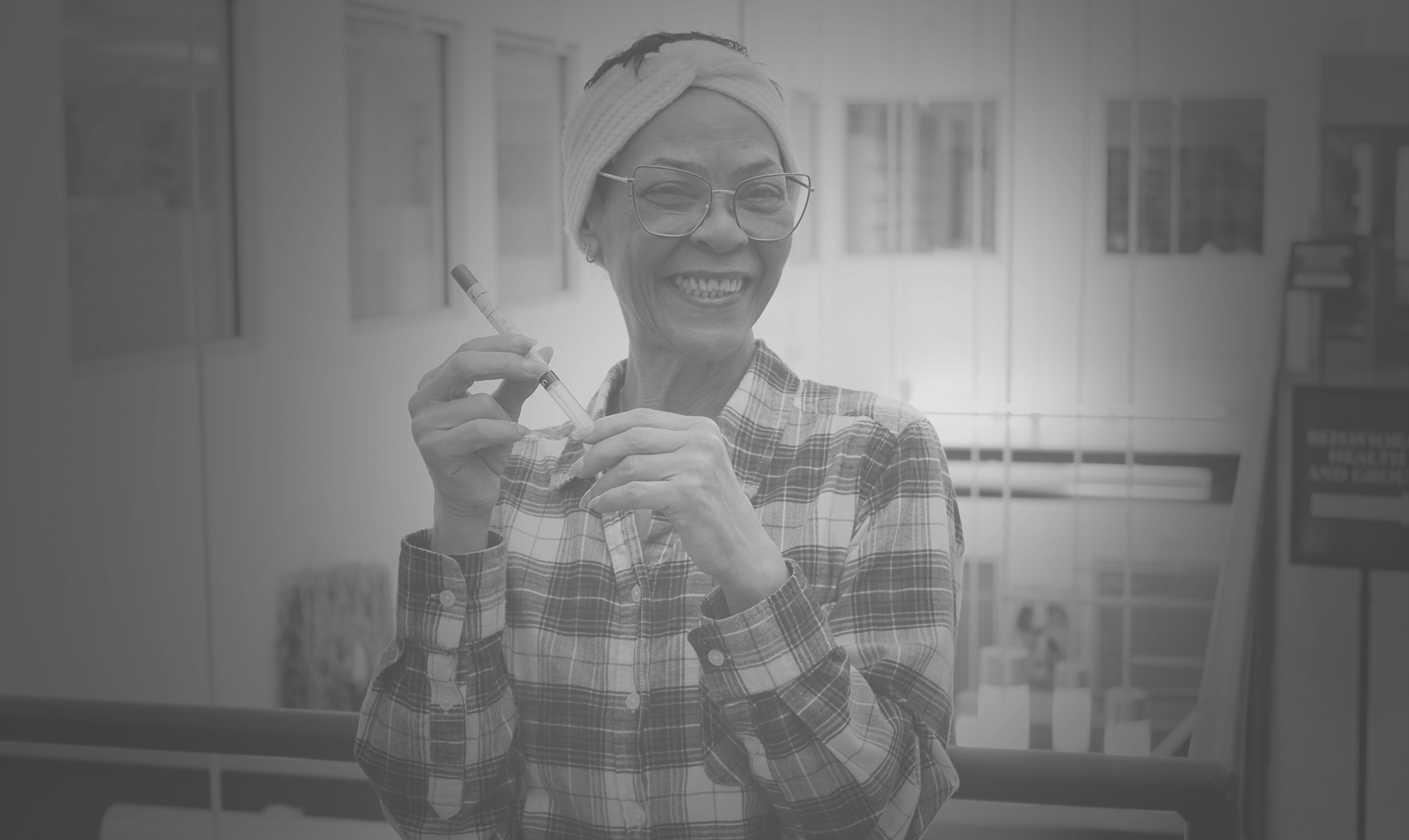 A woman holds an HPV self-swab test tube and a container of solution.