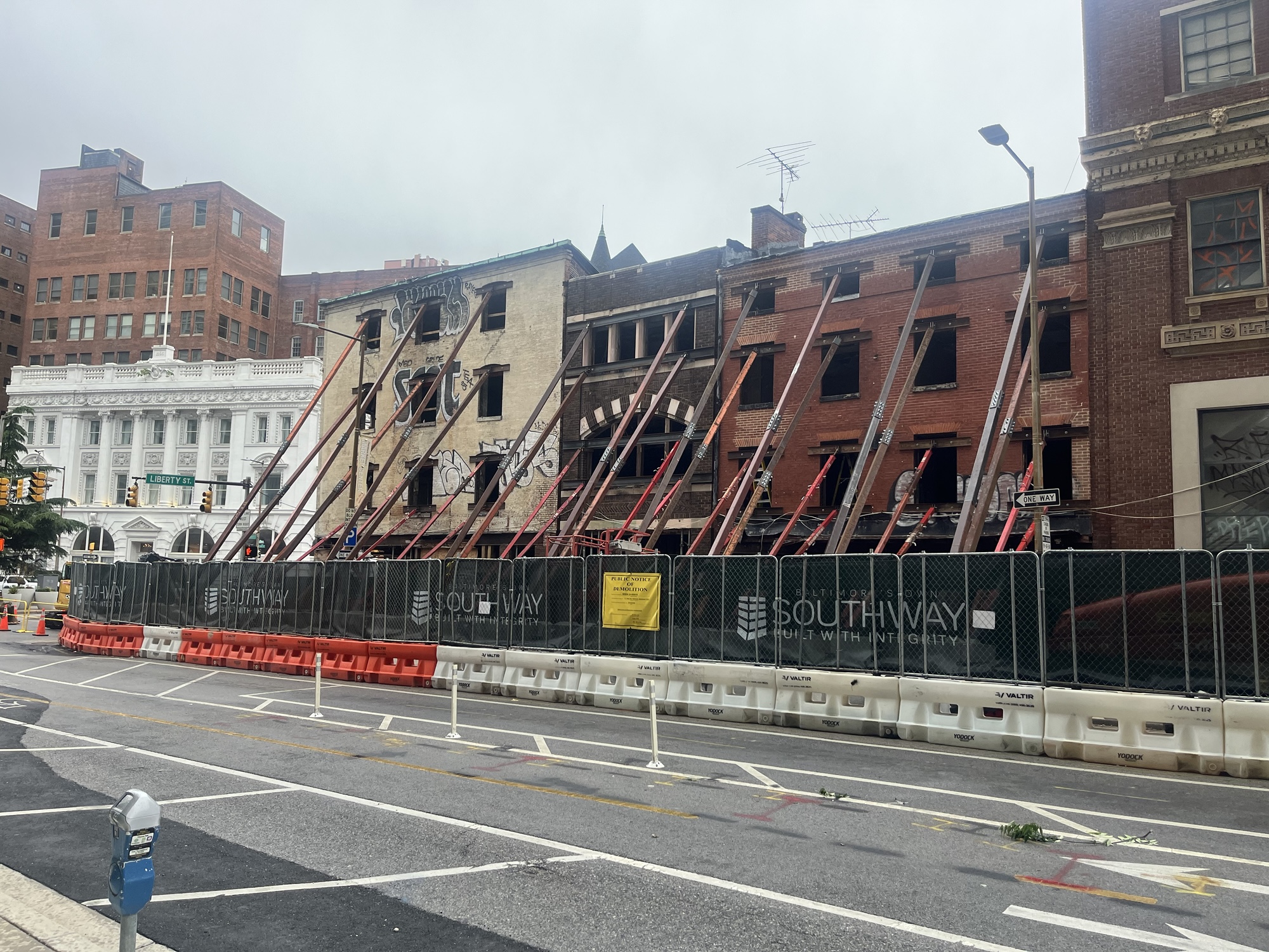 Shoring supports the facades of brick buildings under construction.