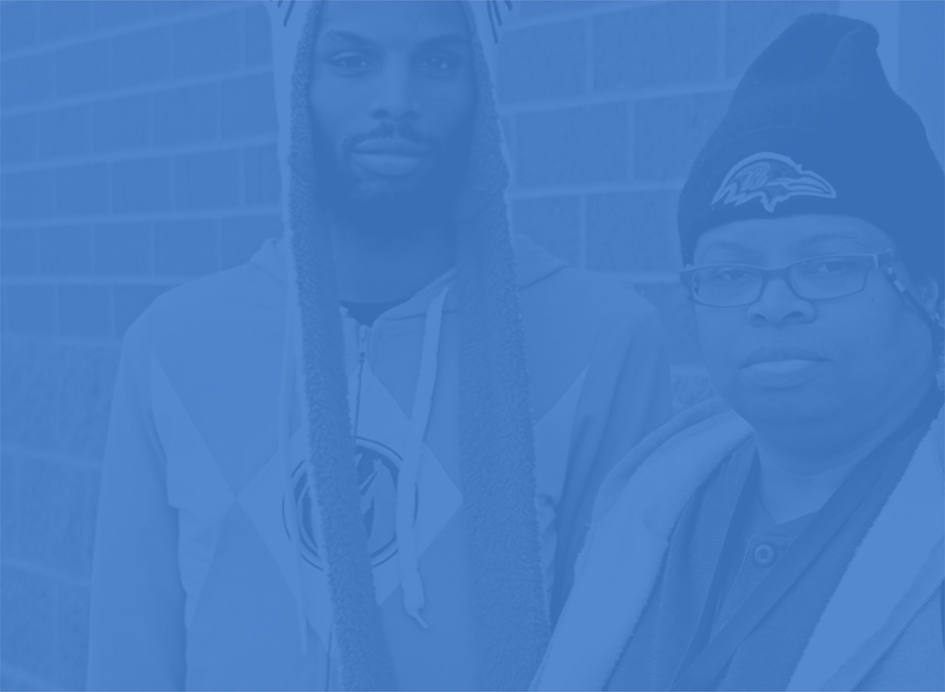 Two people in front of a brick wall