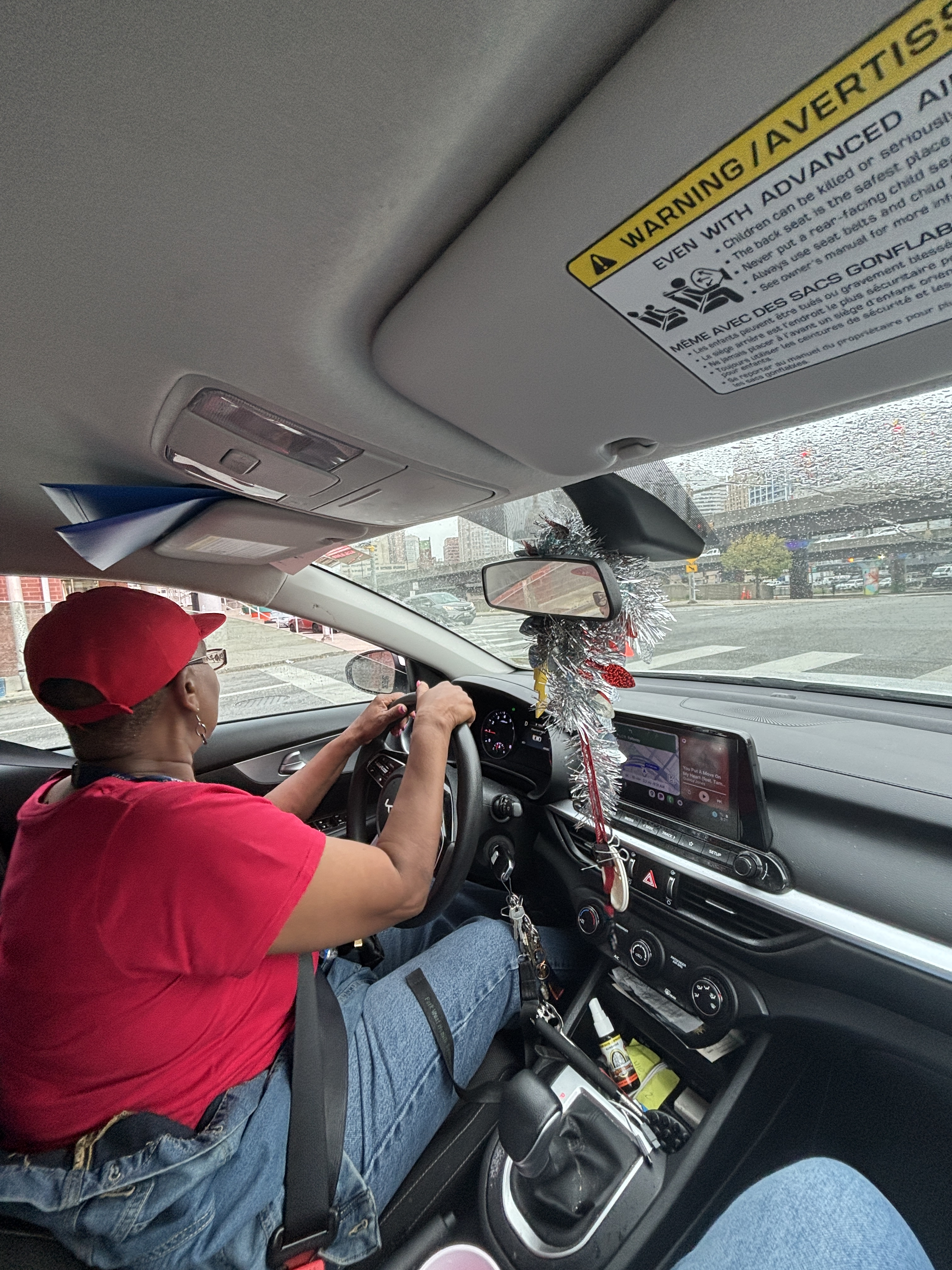 The interior of a car driven by a woman wearing a red hat and red shirt.