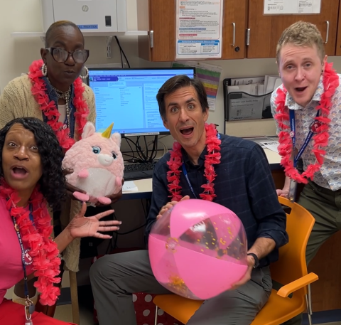 Staff wear pink boas while sitting in an office