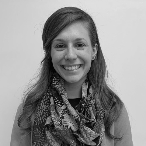 A black and white headshot of a light-skinned woman with long hair.