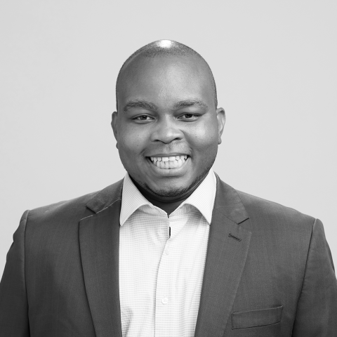 A black and white headshot of a medium-skinned man wearing a collared shirt.