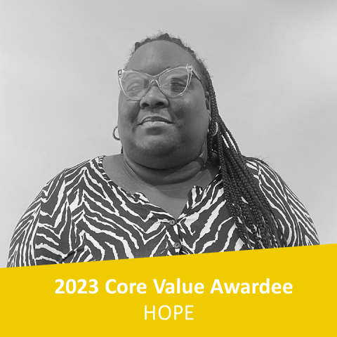 A black and white headshot of a dark-skinned woman with long braids.
