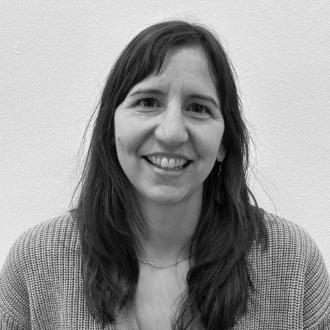 A black and white headshot of a light-skinned woman with long dark hair.