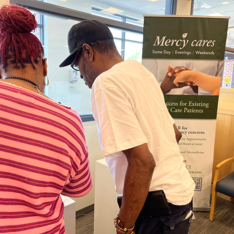 A woman helps a man check in at the hospital.