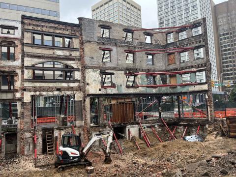 Building facades and an empty dirt area where excavators are working.