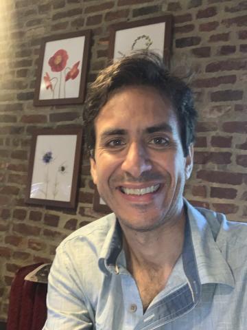 Max Romano smiling in front of a brick wall