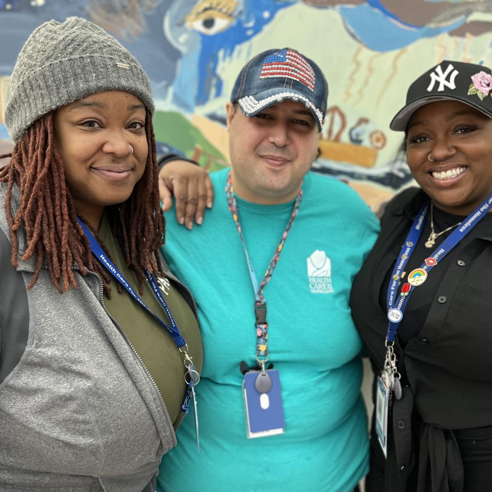 A dark-skinned woman with a gray beanie, a medium-skinned man with a denim baseball cap and a dark-skinned woman with a black baseball cap