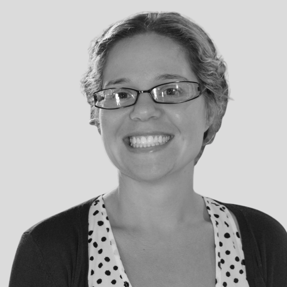 A light-skinned woman with light hair pulled back and glasses.