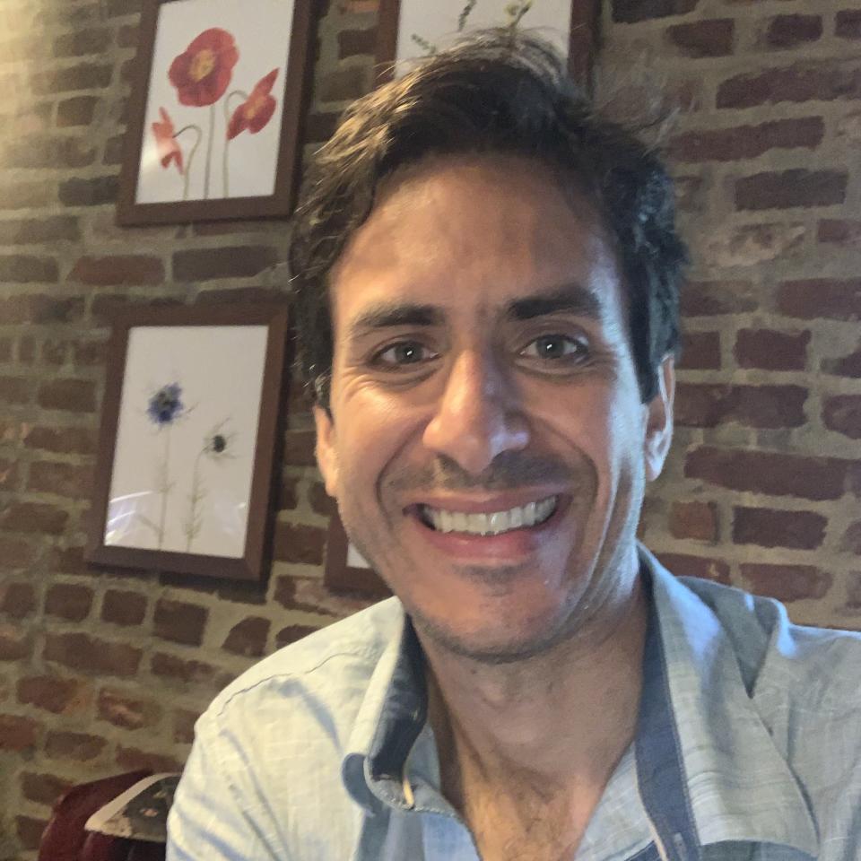 Max Romano smiling in front of a brick wall