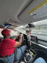 Interior of a car. A woman in a red hat is driving.
