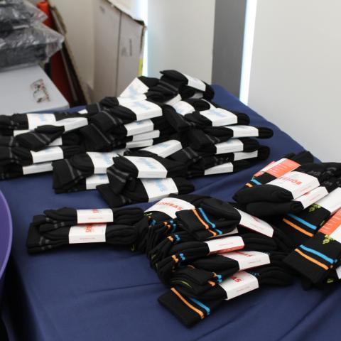 A table full of unopened packs of black socks are ready to be handed out.  