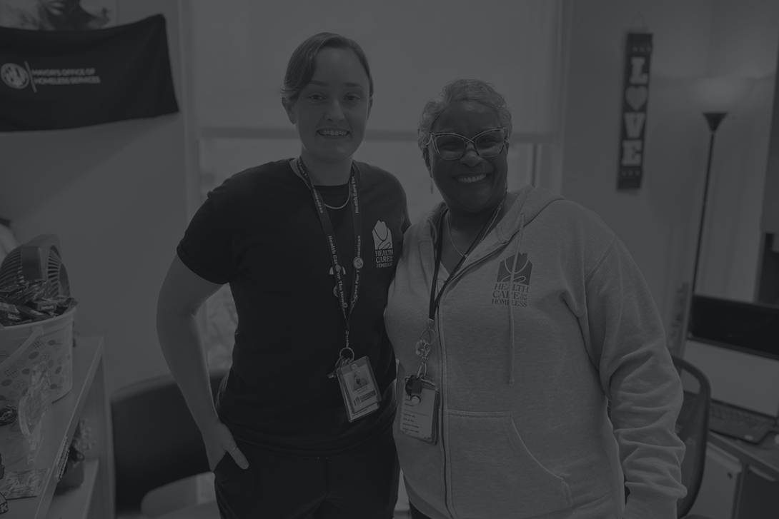 A light-skinned person with short hair stands next to a dark-skinned woman with glasses and short hair.