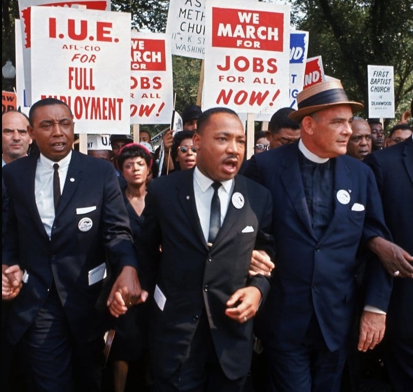 Martin Luther King, Jr. holding hands with other protesters [(R-L) Rabbi Joachim Prinz, unident., Eugene Carson Blake, Martin Luther King, Floyd McKissick, Matthew Ahmann & John Lewis.] outside.